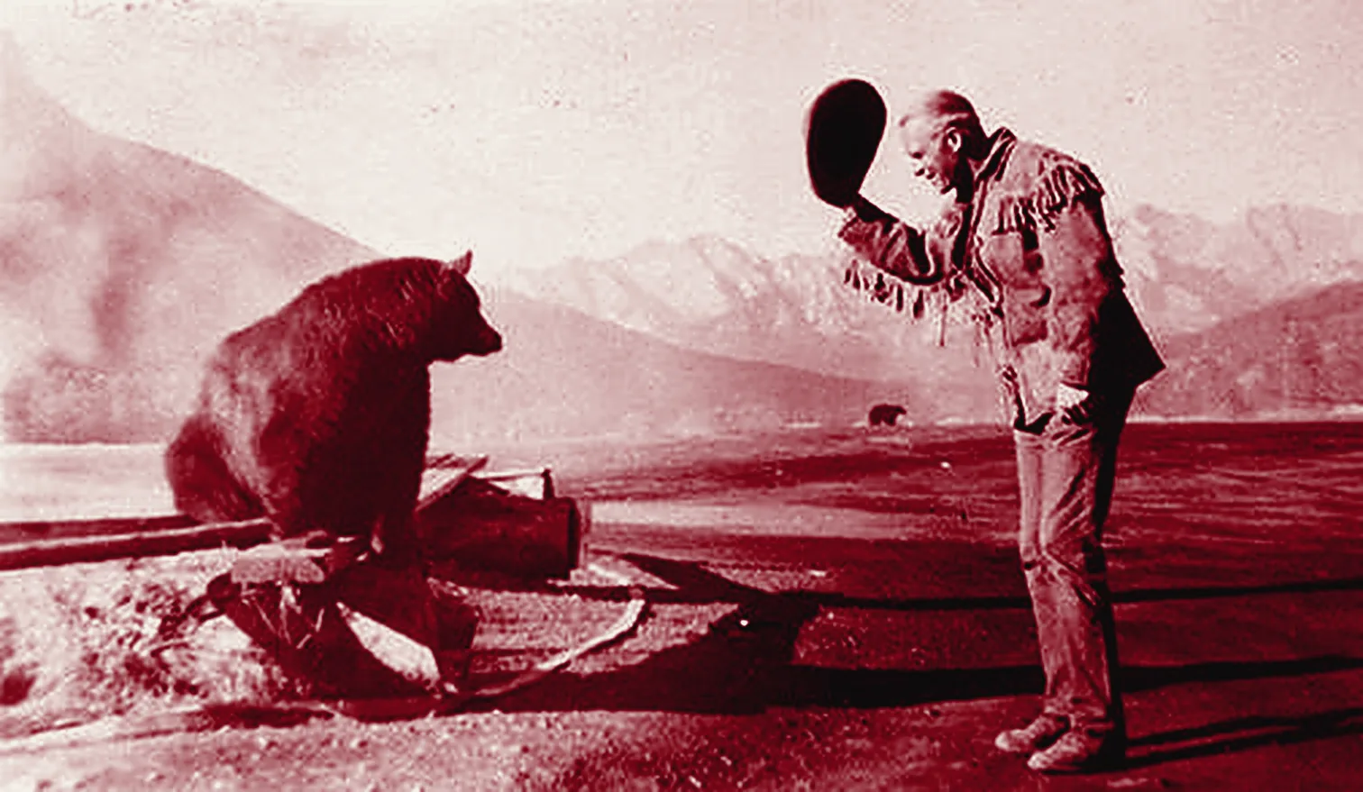 Oxblood duotone of a 1950 photograph near Banff: a man in a fringed jacket tips his hat to a bear